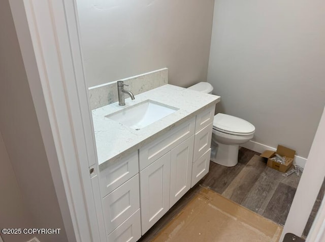 bathroom featuring toilet, vanity, and wood finished floors