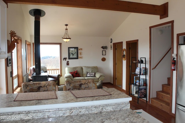 living room featuring vaulted ceiling with beams, a wood stove, stairs, and dark wood-style floors