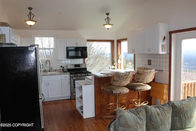 kitchen with decorative backsplash, a kitchen breakfast bar, a sink, white cabinets, and stainless steel appliances