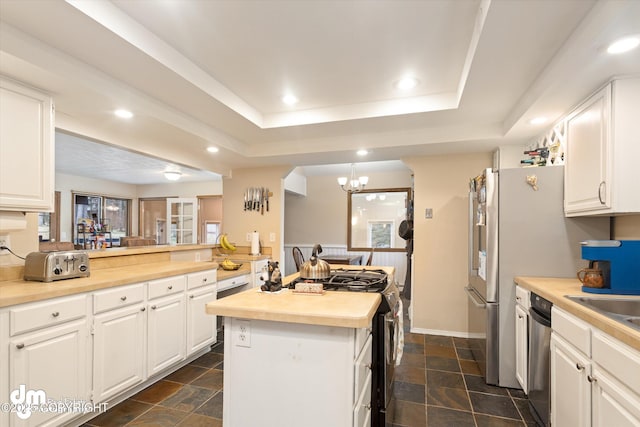 kitchen featuring wood counters, stainless steel gas range, a center island, and stone tile floors