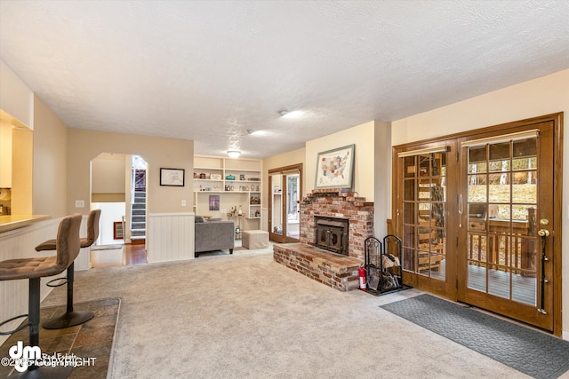 living room featuring carpet floors, arched walkways, a textured ceiling, and built in features