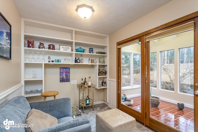 sitting room featuring built in features, a wainscoted wall, and a textured ceiling