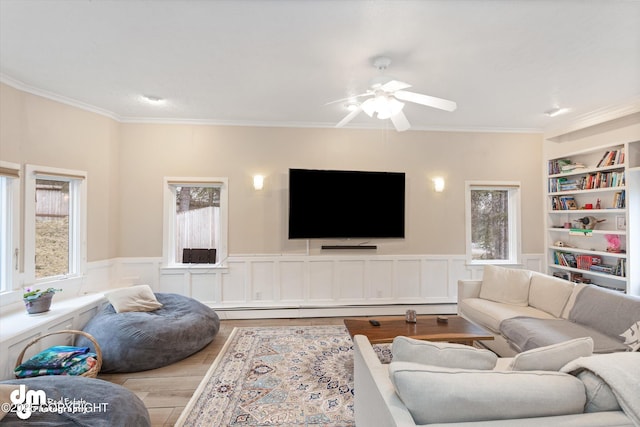 living area featuring ornamental molding, a ceiling fan, wood finished floors, and a wealth of natural light