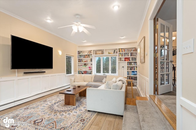 living area with a baseboard radiator, ornamental molding, a ceiling fan, and wood finished floors