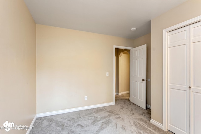 unfurnished bedroom with baseboards, carpet, and a closet