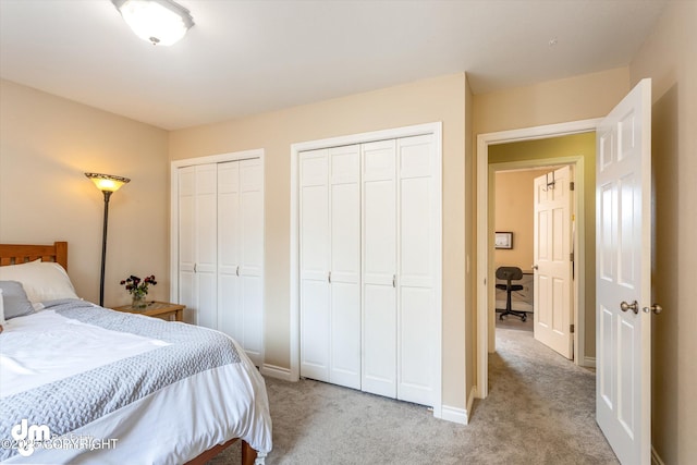 bedroom featuring baseboards, multiple closets, and light carpet