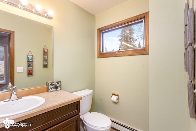 half bathroom featuring vanity, a baseboard heating unit, and toilet