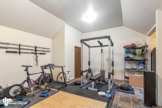 workout area featuring baseboards, vaulted ceiling, and stone finish flooring