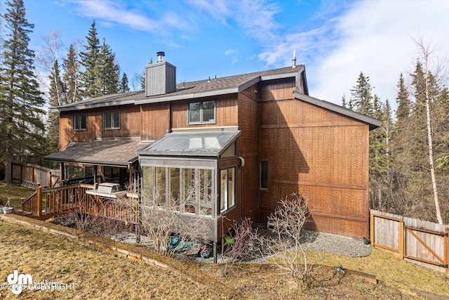 rear view of house featuring a shingled roof, fence, and a chimney