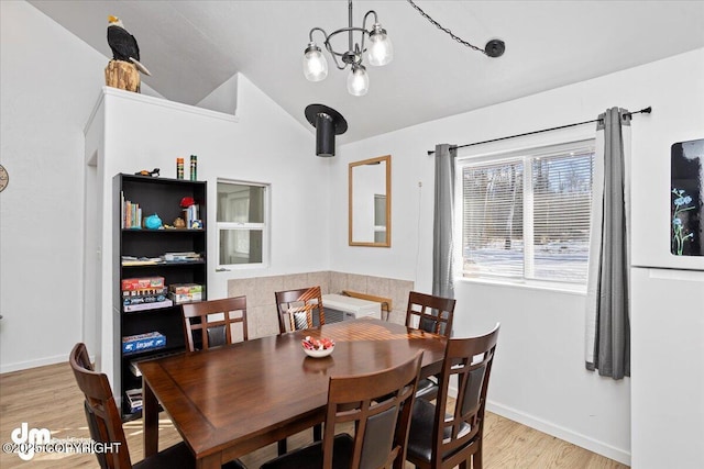 dining room featuring baseboards, light wood-style flooring, lofted ceiling, and a notable chandelier