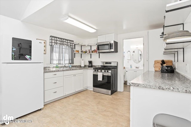 kitchen featuring light countertops, stainless steel appliances, open shelves, and white cabinetry