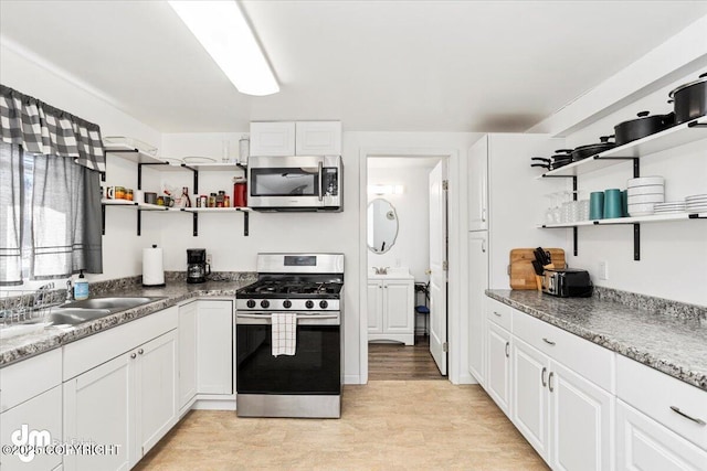 kitchen featuring open shelves, a sink, appliances with stainless steel finishes, and white cabinetry