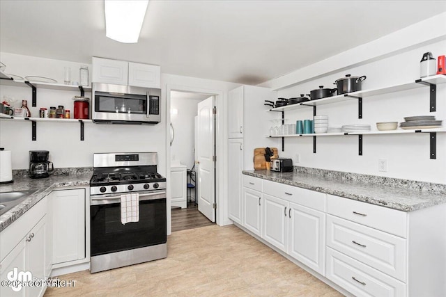 kitchen featuring white cabinets, open shelves, light stone counters, light wood-style floors, and stainless steel appliances