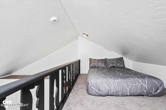 carpeted bedroom with a textured ceiling, vaulted ceiling, and baseboards