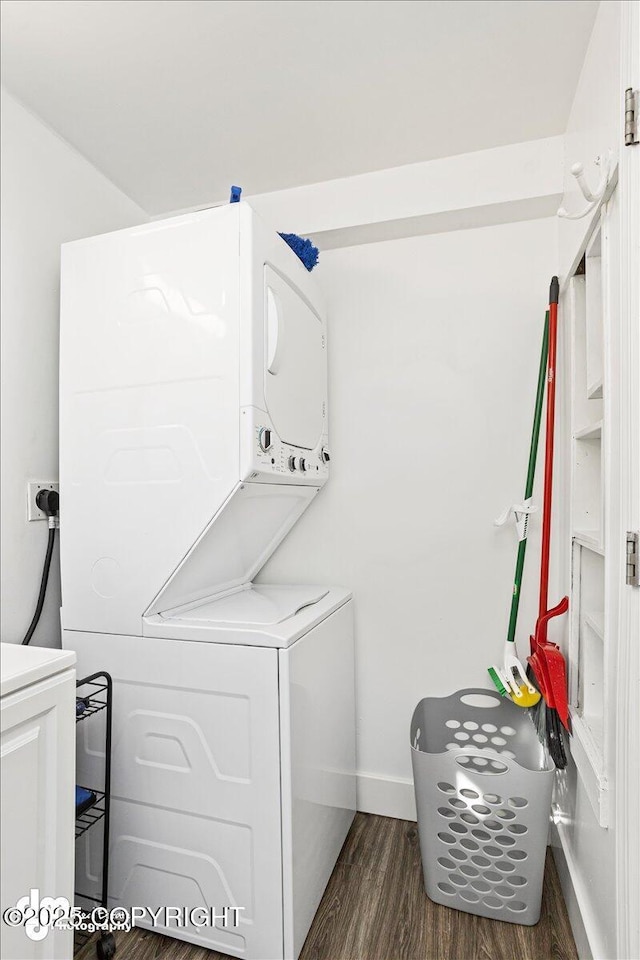 clothes washing area with laundry area, stacked washing maching and dryer, baseboards, and dark wood-type flooring