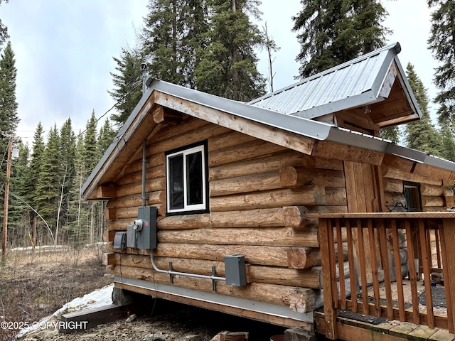 view of side of property featuring metal roof, a wooden deck, and log exterior