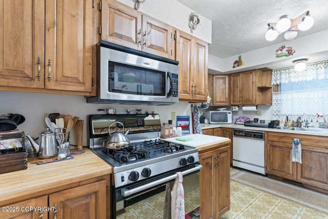 23675 Glacier View Dr, Eagle River, AK 99577 - kitchen featuring stainless steel appliances, wood counters, brown cabinetry, and a sink