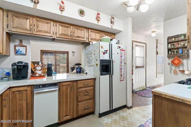 23675 Glacier View Dr, Eagle River, AK 99577 - kitchen featuring light countertops, white fridge with ice dispenser, brown cabinetry, and a textured ceiling