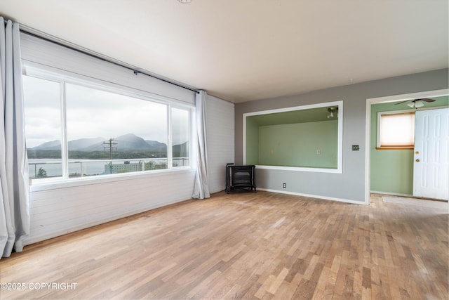 430 Washington St, Ketchikan, AK 99901 - empty room featuring baseboards, a wood stove, a mountain view, and light wood-style flooring