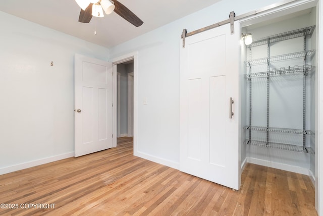 430 Washington St, Ketchikan, AK 99901 - unfurnished bedroom with light wood-type flooring, a barn door, baseboards, and a ceiling fan