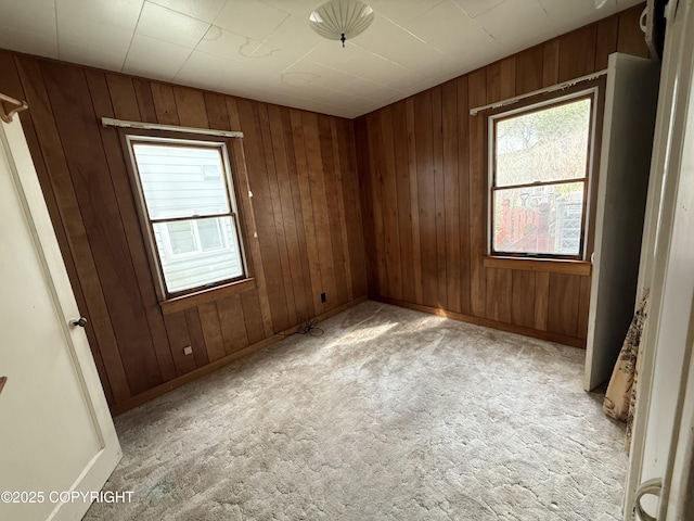 unfurnished room featuring baseboards, light carpet, and wood walls