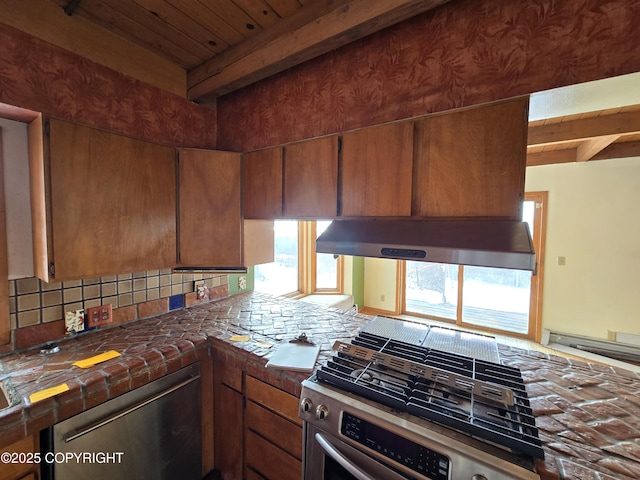 kitchen with beamed ceiling, backsplash, under cabinet range hood, and stainless steel appliances