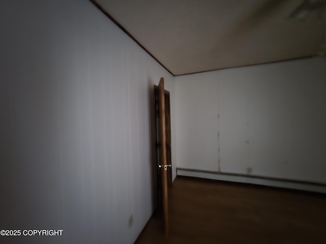 spare room featuring a baseboard heating unit and wood finished floors