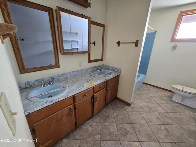 bathroom featuring a sink, baseboards, toilet, and double vanity