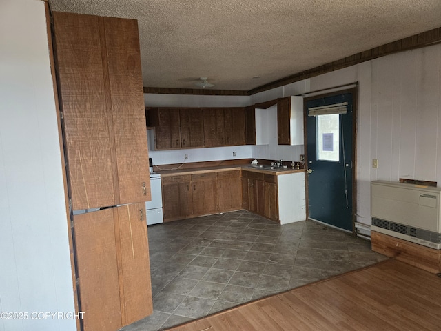 kitchen with range with electric cooktop, a textured ceiling, brown cabinets, a sink, and heating unit
