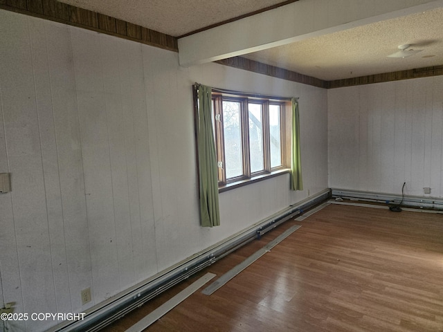 spare room featuring a textured ceiling, wood finished floors, and wooden walls