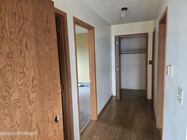 hall featuring dark wood-style flooring and a textured ceiling