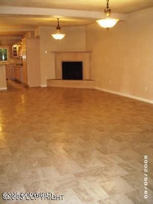 unfurnished living room featuring baseboards and a fireplace with raised hearth