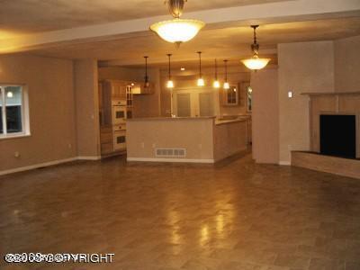 unfurnished living room featuring visible vents, a fireplace with raised hearth, baseboards, and beamed ceiling