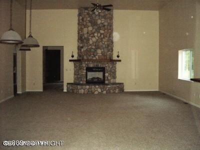 unfurnished living room with baseboards, a ceiling fan, carpet flooring, and a stone fireplace