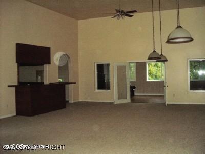 unfurnished living room featuring baseboards, ceiling fan, carpet, and a towering ceiling