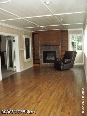 living area featuring baseboards, a tiled fireplace, and wood finished floors