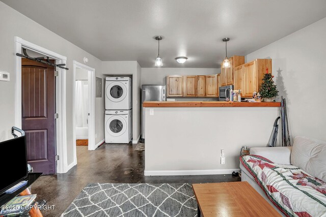 living area featuring baseboards, stacked washer and dryer, and finished concrete floors
