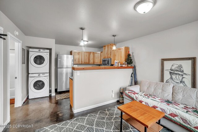 living area with stacked washing maching and dryer, baseboards, and finished concrete flooring