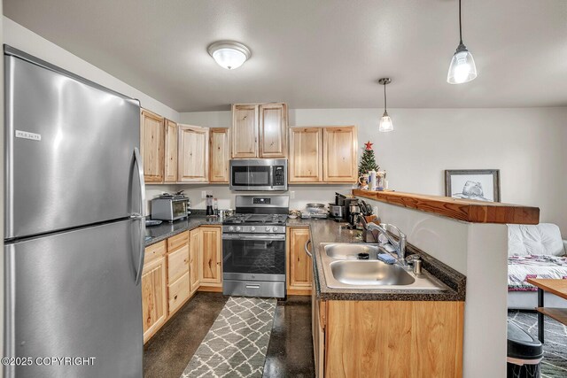 kitchen with dark countertops, a sink, light brown cabinets, stainless steel appliances, and a peninsula