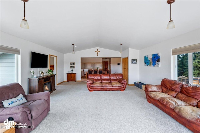 carpeted living area featuring lofted ceiling, baseboards, and a glass covered fireplace