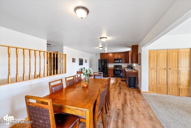 dining area with light wood finished floors and a textured ceiling
