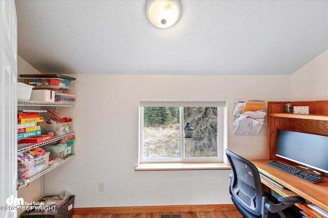 home office featuring vaulted ceiling, visible vents, and wood finished floors
