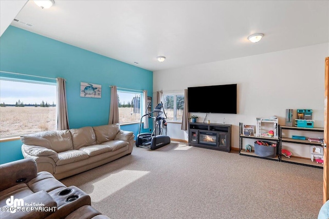 carpeted living room with baseboards, a glass covered fireplace, and visible vents
