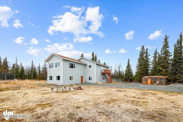 back of house featuring a deck, stairway, an outbuilding, and a greenhouse
