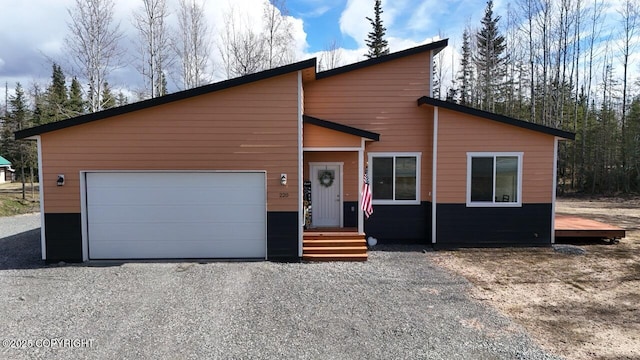 view of front of property with an attached garage and gravel driveway