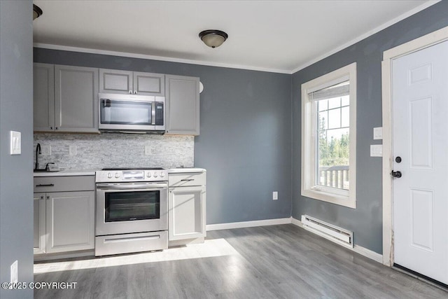 1369 Morning Glory Loop, North Pole, AK 99705 - kitchen with stainless steel appliances, a baseboard heating unit, gray cabinetry, backsplash, and wood finished floors