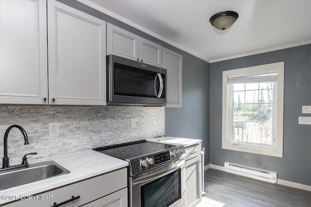 1369 Morning Glory Loop, North Pole, AK 99705 - kitchen featuring appliances with stainless steel finishes, a baseboard radiator, a sink, wood finished floors, and tasteful backsplash