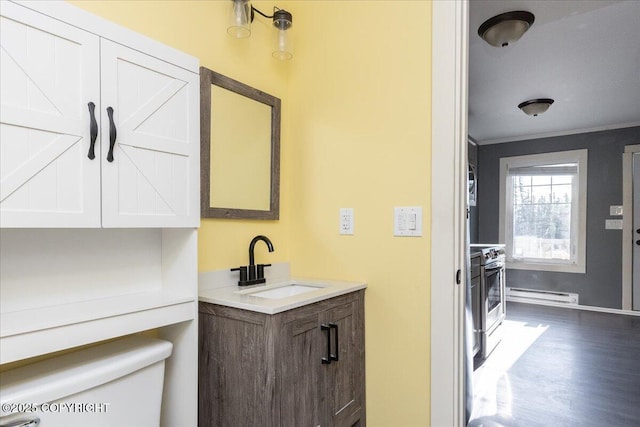 1369 Morning Glory Loop, North Pole, AK 99705 - half bathroom with a baseboard heating unit, toilet, vanity, wood finished floors, and crown molding