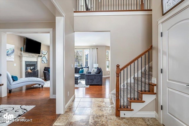 7865 S Settlers Bay Dr, Wasilla, AK 99623 - entryway featuring a high end fireplace, wood finished floors, baseboards, a high ceiling, and stairs