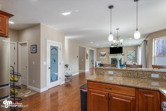 7865 S Settlers Bay Dr, Wasilla, AK 99623 - kitchen featuring brown cabinets, a fireplace, dark wood-style flooring, and decorative light fixtures